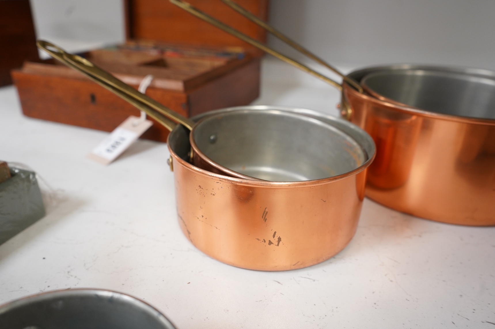 A graduated set of five brass handled copper saucepans, largest 36cm including handle.